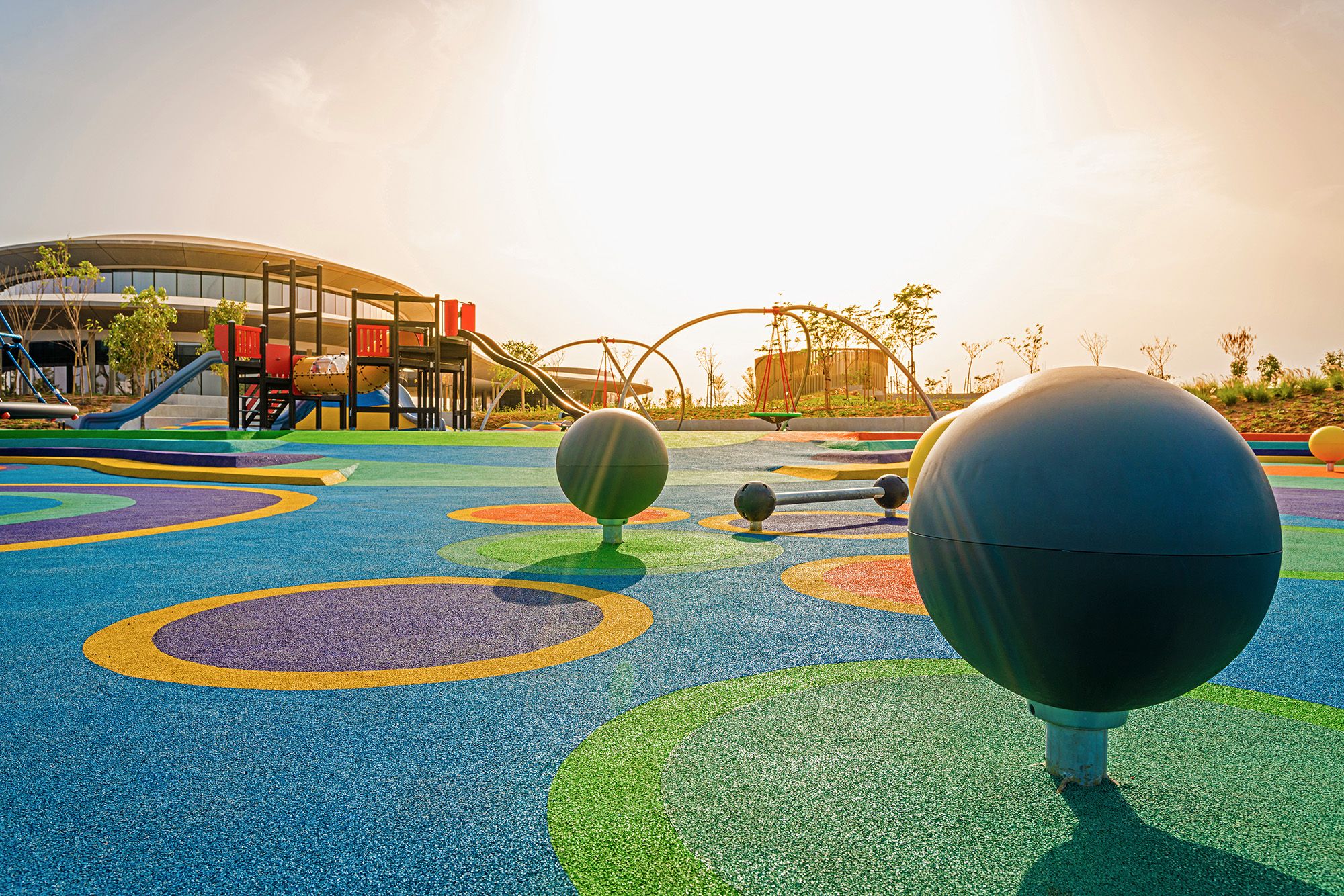 sun shines over playground equipment and rosehill tpv colored rubber granules at playscape at madar 
